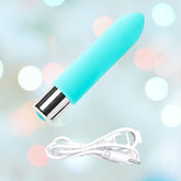 A turquoise, bullet-shaped object with a metallic base, resembling a compact electronic device, is accompanied by its white USB charging cable. This is the VeDO Bam Mini Rechargeable Bullet Vibrator in turquoise, offering powerful vibration modes enhanced by soft pastel colors and lights.